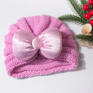 Détail du bonnet en tricot rose pour bébé avec un grand nœud en satin et maille côtelée