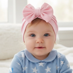Close-up of baby waffle turban hat featuring a large soft pink bow and ribbed cotton texture