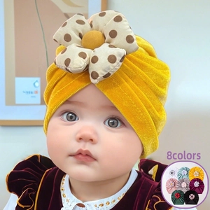 Detailed view of yellow velvet baby turban featuring a large polka dot fabric flower