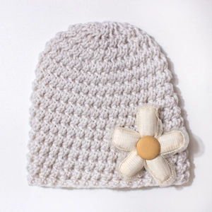 Detailed close-up of handmade crochet baby beanie with a large decorative fabric flower