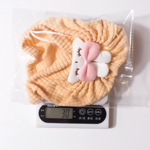 Detail showing soft ribbed texture and rabbit embroidery on beige baby beanie in package