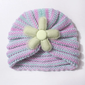 Detailed knit pattern on baby beanie featuring pink stripes and a green flower accent
