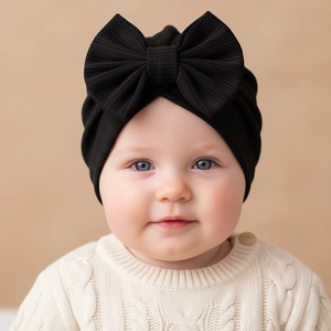 Detail shot of baby turban hat featuring a large black bow and soft ribbed knit texture