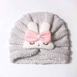 Close-up of baby turban hat featuring a cute white bunny patch and pink satin bow detail