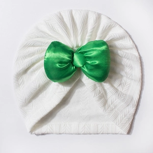 Détail du bonnet en tricot pour bébé avec tissu blanc texturé et grand nœud en satin