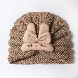 Detail of baby knitted hat featuring a pink plush bunny ear bow and cute embroidery
