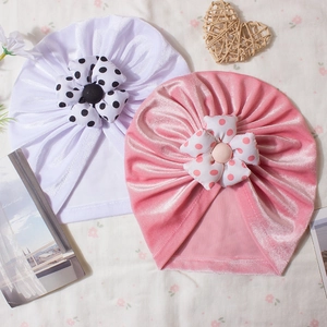 Close-up of pink and white velvet baby turban hats with large polka dot floral details