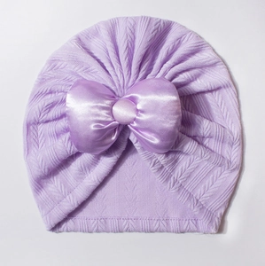Gros plan détaillé d'un bonnet turban pour bébé lavande avec un grand nœud en satin élégant