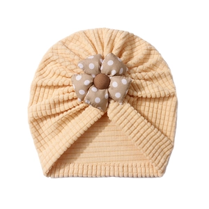 Detailed texture of yellow waffle knit baby turban hat with a polka dot floral fabric accent