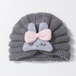Close-up of cute grey knitted baby hat with rabbit design and pink bow detail