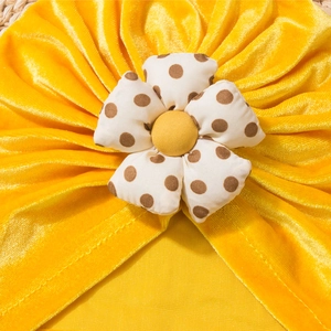 Detailed view of yellow velvet baby turban featuring a decorative polka dot floral knot