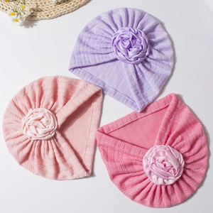 Three soft cable knit baby turban hats with large satin flowers in various soft colors