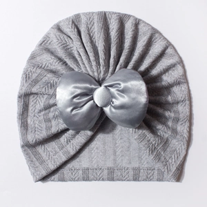 Détail du bonnet turban gris pour bébé avec maille texturée et grand nœud décoratif en satin