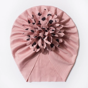 Détail du bonnet rose pour bébé avec grande fleur en tissu ornée de cœurs noirs