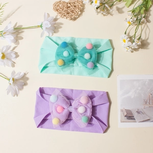 Soft newborn headbands with mint and purple mesh bows filled with colorful pom-poms