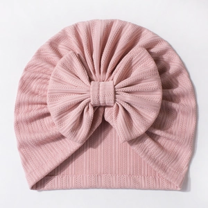 Detailed view of pink rib-knit baby turban hat with a soft decorative fabric bow