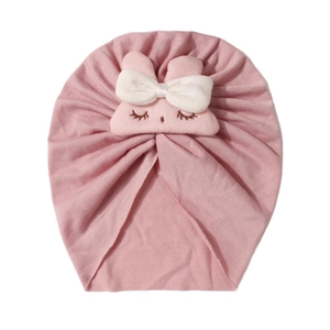 Dettaglio del cappello a turbante rosa per neonati con coniglietto e fiocco bianco