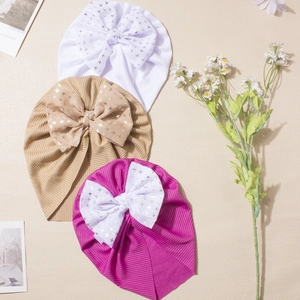 Close-up of ribbed knit baby turban hats with large silver star print bow decorations