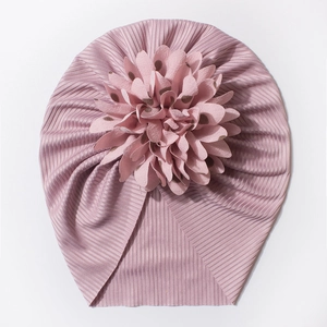 Gros plan du bonnet rose pour bébé avec grande fleur à pois et texture en maille côtelée