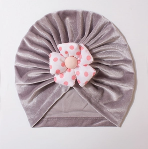 Detailed view of grey velvet baby turban hat with a large red polka dot fabric flower