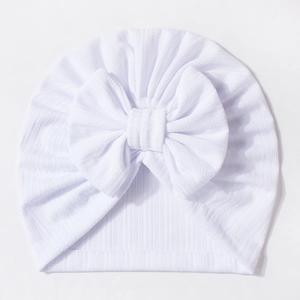 Detailed texture of white waffle knit baby hat with a large decorative bow tie