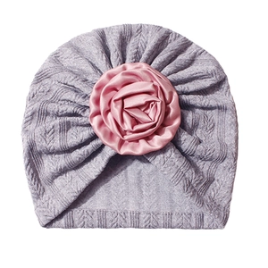 Detail of baby turban hat featuring a large pink satin rose on soft purple knit fabric
