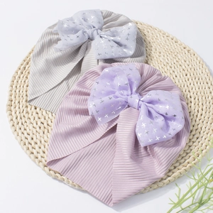 Detail of baby turban hats featuring large mesh bows and silver star pattern print