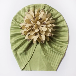 Détail de bonnet turban bébé vert herbe côtelé avec décor fleur beige à pois