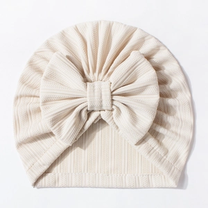 Close-up of baby waffle turban hat with large bow detail in soft cream color