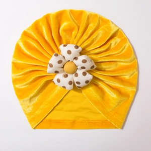 Detail view of the yellow velvet baby turban hat with a spotted fabric flower