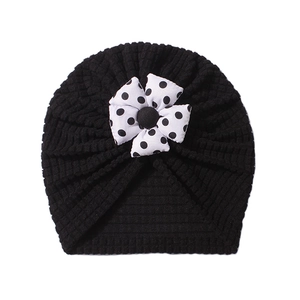 Detail of waffle texture baby turban hat in black with white polka dot bow