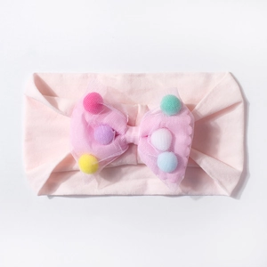 Detailed close-up of pink baby headband with mesh bow filled with colorful pom-poms