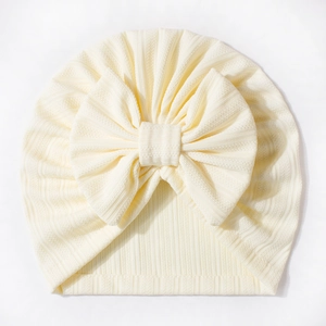 Close-up of baby waffle turban hat with a large bow detail in soft cream rib fabric