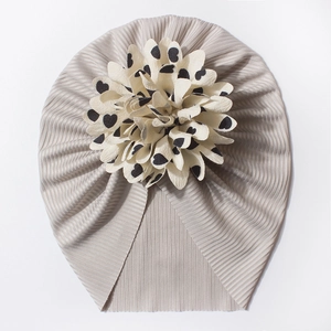 Détail d'un bonnet turban gris pour bébé avec une grande fleur crème à motifs de cœurs