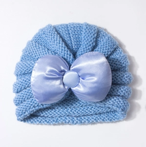 Détail à plat d'un bonnet tricoté bleu clair pour bébé avec un grand nœud en satin