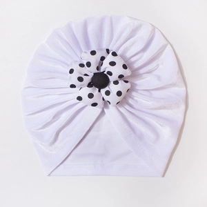 Detail of baby velvet turban hat showing polka dot flower and soft pleated fabric