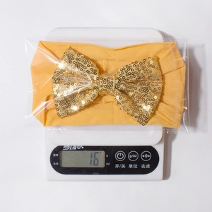 Mesure du poids d'un bandeau jaune pour bébé avec nœud à paillettes dorées