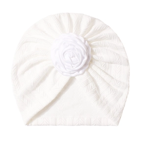 Detail of white baby turban with delicate knit texture and a large floral fabric rose