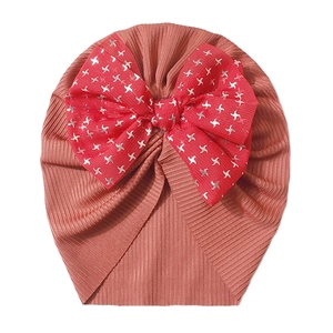 Detailed texture of ribbed coral pink baby turban hat with a large red glitter star bow