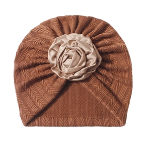 Detail of baby turban hat in caramel knit with a champagne satin rose accent
