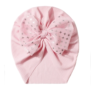 Close-up of pink ribbed baby turban hat featuring a large mesh bow with silver star patterns
