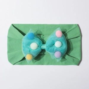Detail of mint green baby headband with mesh bow filled with colorful pom-poms