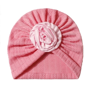 Detailed texture of pink knitted baby turban hat with a large satin rose decoration
