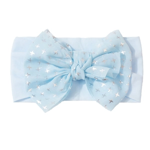 Détail d'un bandeau bébé bleu clair orné d'un grand nœud avec imprimé étoiles argent