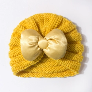Vue détaillée du bonnet en tricot pour bébé jaune avec un grand nœud en satin soyeux