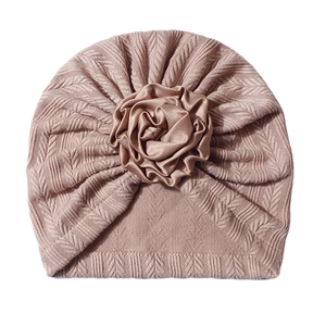 Close-up of pink knit baby beanie featuring a large satin flower and braided texture