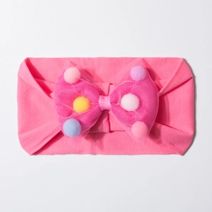Close-up of baby headband with rose pink mesh bow and colorful plush pom-poms details