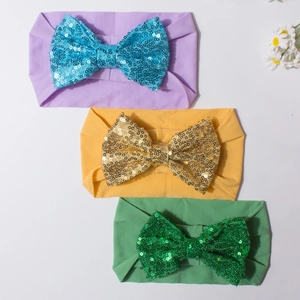 Vue détaillée de trois bandeaux pour bébé avec grands nœuds à paillettes en violet et jaune