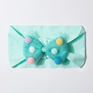 Detail view of mint green baby headband with soft mesh bow and colorful pom-poms