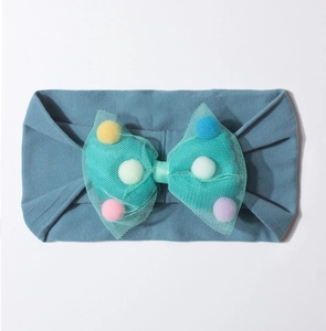 Detail of baby headband with blue knit band and mesh bow filled with colorful pom-poms
